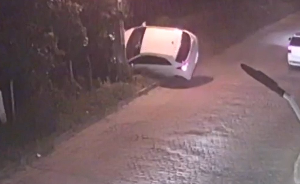 Câmera de segurança registrou o momento em que um carro tenta desviar de um buraco na Estrada do Francês, mas acaba tombando na via  — Foto: Reprodução/TV Subaé