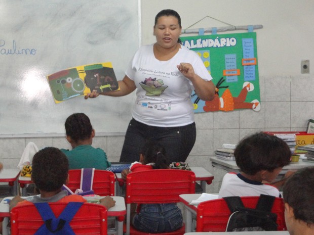 Promotora de leitura lê uma história para as crianças e depois elas podem pegar um livro emprestado (Foto: Juliana Barros/Livro em Roda)
