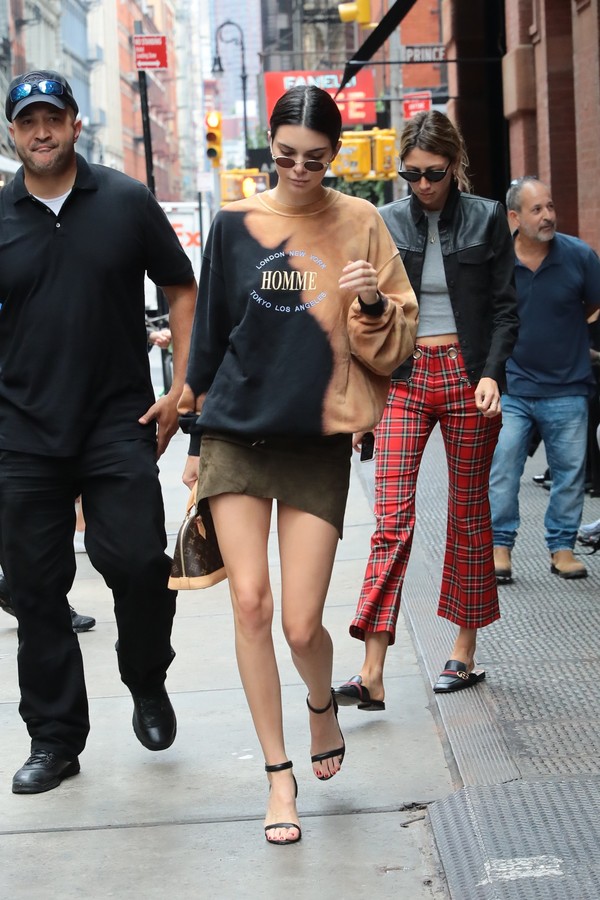 New York, NY  - Kendall Jenner briefly poses for fan pictures as she leaves her hotel. Kendall looks trendy in small oval sunglasses, a tie dyed Homme sweater, olive green suede skirt, black heels and a Louis Vuitton mini bag.Pictured: Kendall Jenner (Foto: INI / BACKGRID)