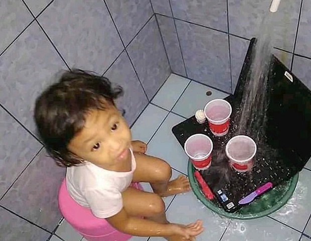 Menina leva o laptop para brincar de mesinha no chuveiro (Foto: Reprodução/Daily Mail)