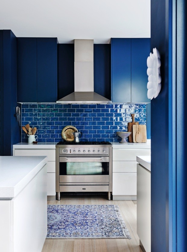 Cozinha. Os azulejos que formam o frontão são da cor Azul Zafiro, mesmo tom usado nos armários. As bancadas brancas e o tapete acrescentam um ar de sofisticação (Foto: Lisa Cohen / Living Inside)