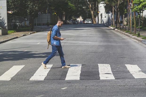 Photo of young man walking at crosswalk on a street. (Foto: Getty Images)