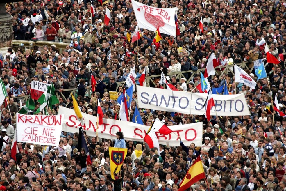 Imagem de 2005 mostra fieis com cartazes pedindo para que João Paulo II fosse considerado santo, durante seu funeral no Vaticano.  — Foto: Luca Bruno/ AP 