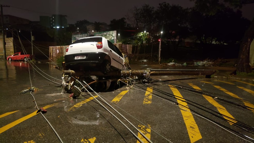 Carro foi levado pela enxurrada até parar sobre um poste caído na rua — Foto: Danilo Girundi / TV Globo