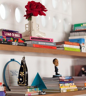 Livros e objetos de decoração sobre as prateleiras de madeira. O apartamento é projeto do arquiteto Felipe Hass