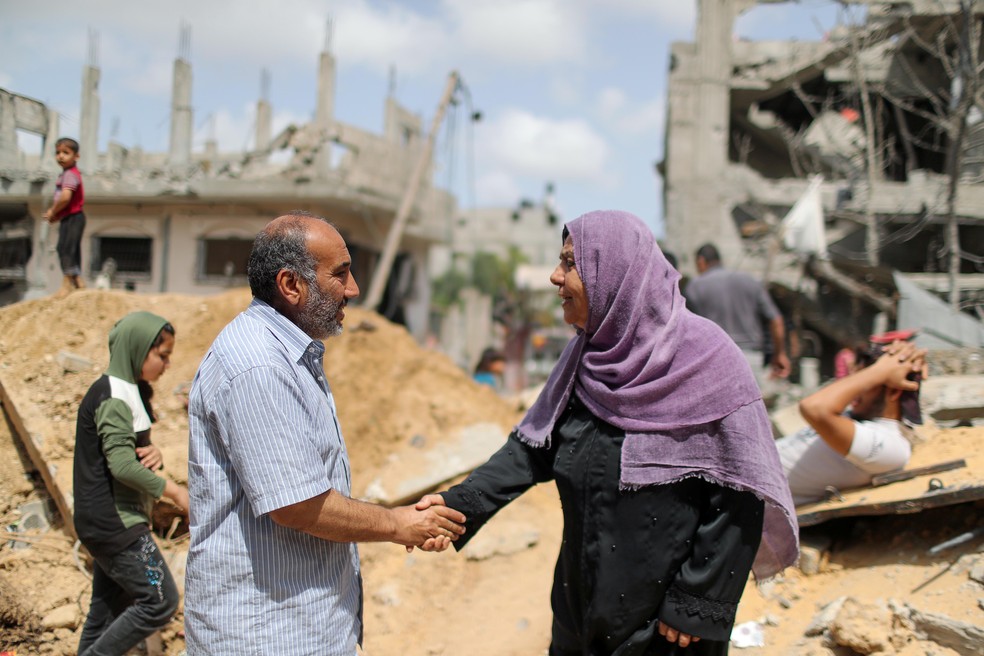Palestinos apertam as mãos após retornarem para suas casas destruídas após a trégua Israel e Hamas, em Beit Hanoun, no norte da Faixa de Gaza — Foto: Mohammed Salem/Reuters