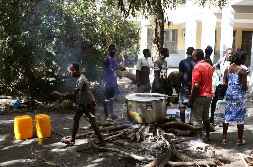 Moradores retirados da vila de Buzi, perto de Beira, em Moçambique, cozinham em acampamento nesta segunda (25) — Foto: Reuters/Siphiwe Sibek
