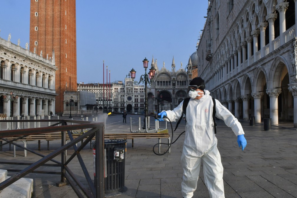 Funcionário municipal pulveriza desinfetante em áreas públicas na Praça de São Marcos, em Veneza, nesta quarta-feira (11)  — Foto: Marco Sabadin / AFP