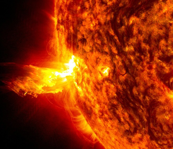 Esta imagem de 20 de junho de 2013 mostra a luz brilhante de uma erupção solar no lado esquerdo do Sol e uma erupção de material solar na atmosfera do astro (Foto: Nasa Goddard)