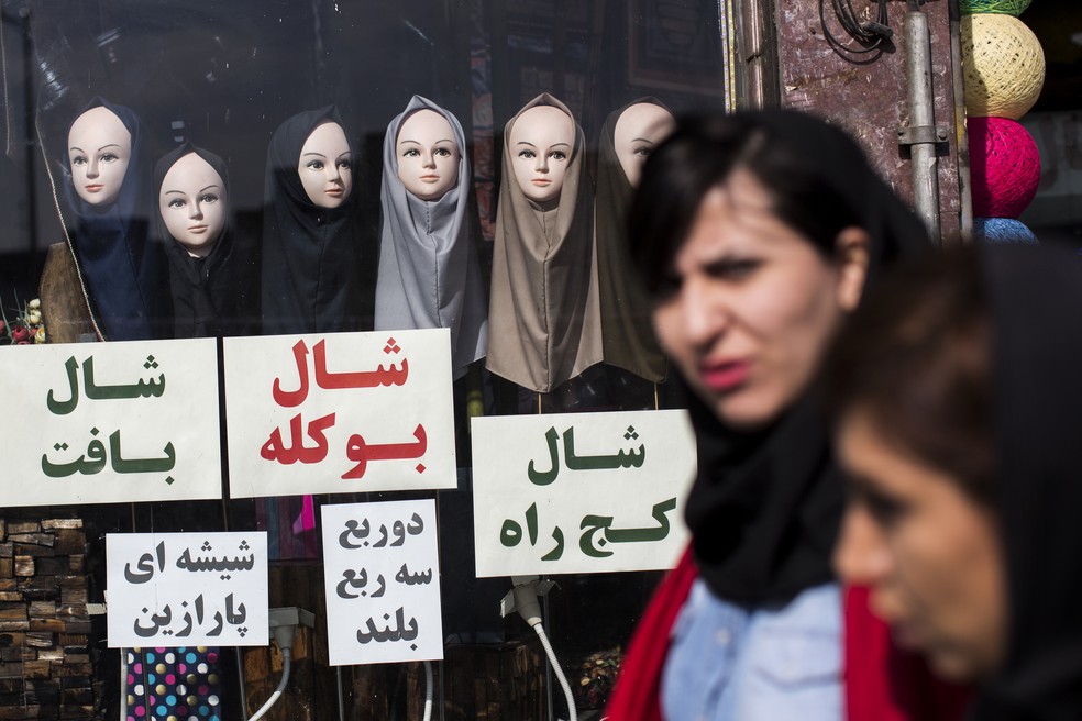 Em imagem de arquivo, mulheres passam em frente à loja de véus em Teerã, capital iraniana (Foto: BEHROUZ MEHRI / AFP)