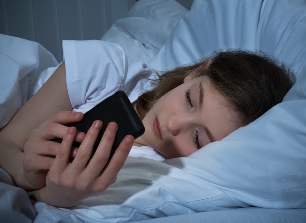 Menina mexendo no celular na cama (Foto: Thinkstock)