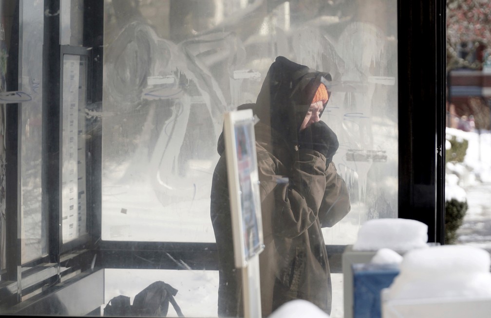 Morador de Pittsfield, Massachusetts, no nordeste dos EUA, se abriga em ponto de ônibus contra onda de frio (Foto: Ben Garver/