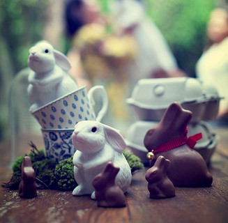 Xícaras empilhadas e bichinhos de porcelana e chocolate decoram a mesa das lembrancinhas, guardadas em caixas de ovos