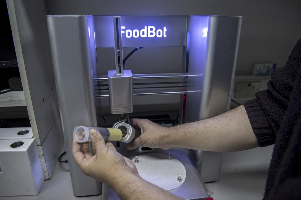 Estudante de engenharia alimental Narcelo Beltran mostra como carregar alimentos em uma impressoa 3D no laboratório da universidade do Chile  — Foto: AFP