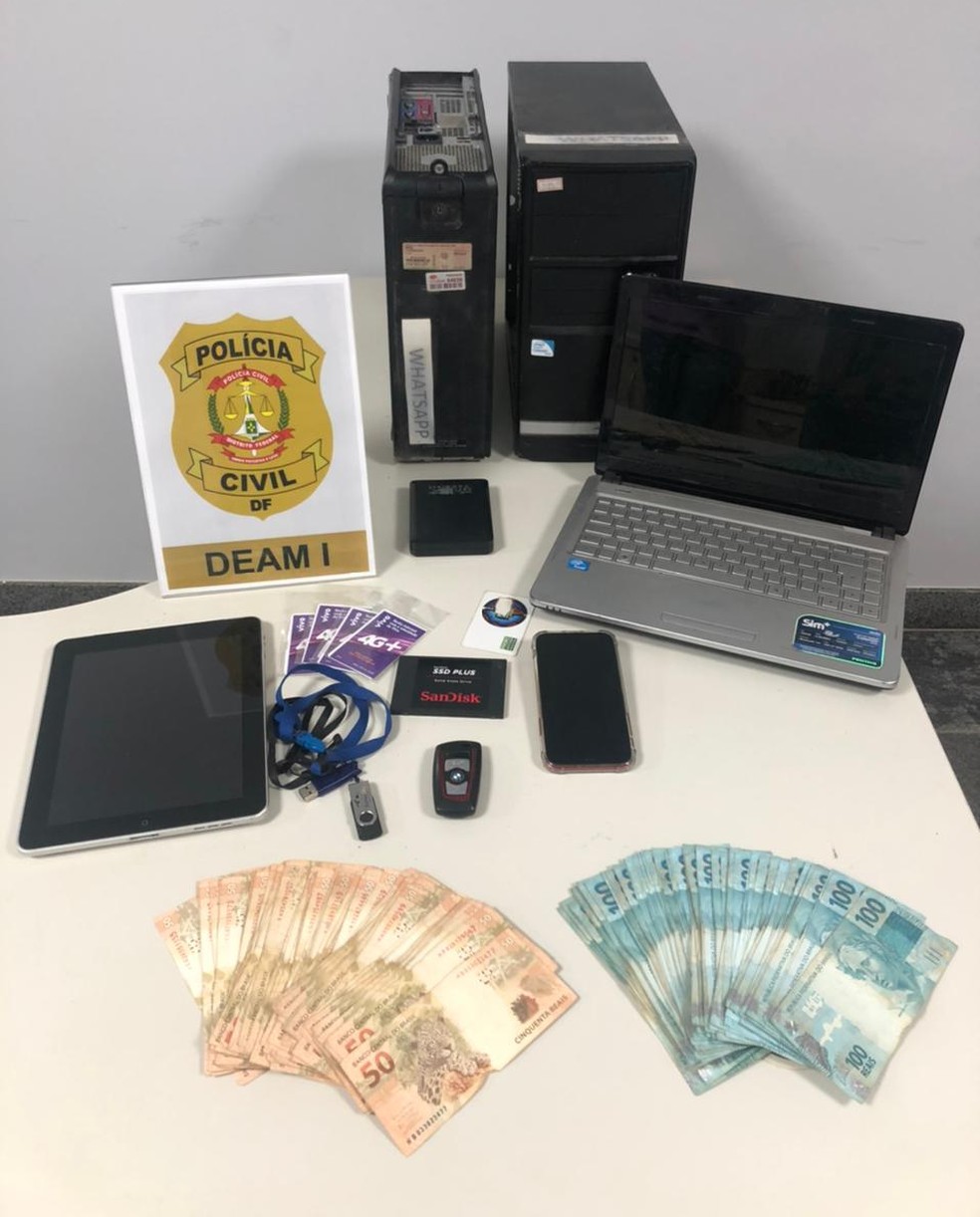 Na casa do suspeito de sugar daddy, policiais da Deam-DF apreenderam dinheiro, celular e computadores — Foto: Polícia Civil do DF /reprodução