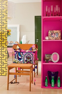 A estante na cor pink acompanha o tom da viga neste apartamento assinado pela arquiteta Andrea Murao. Ao lado, o espelho amplia a sala, que tem piso e paredes em tons neutros