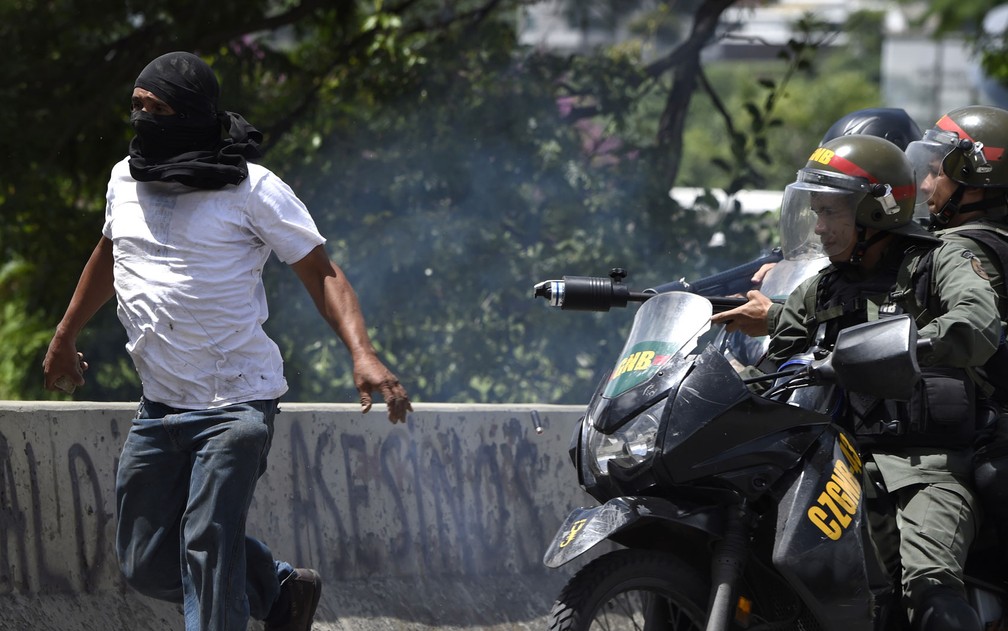 Manifestante é perseguido por membros da Guarda Nacional durante protesto contra o governo em Caracas, na Venezuela, na quinta-feira (20) (Foto: Juan Barreto/AFP)