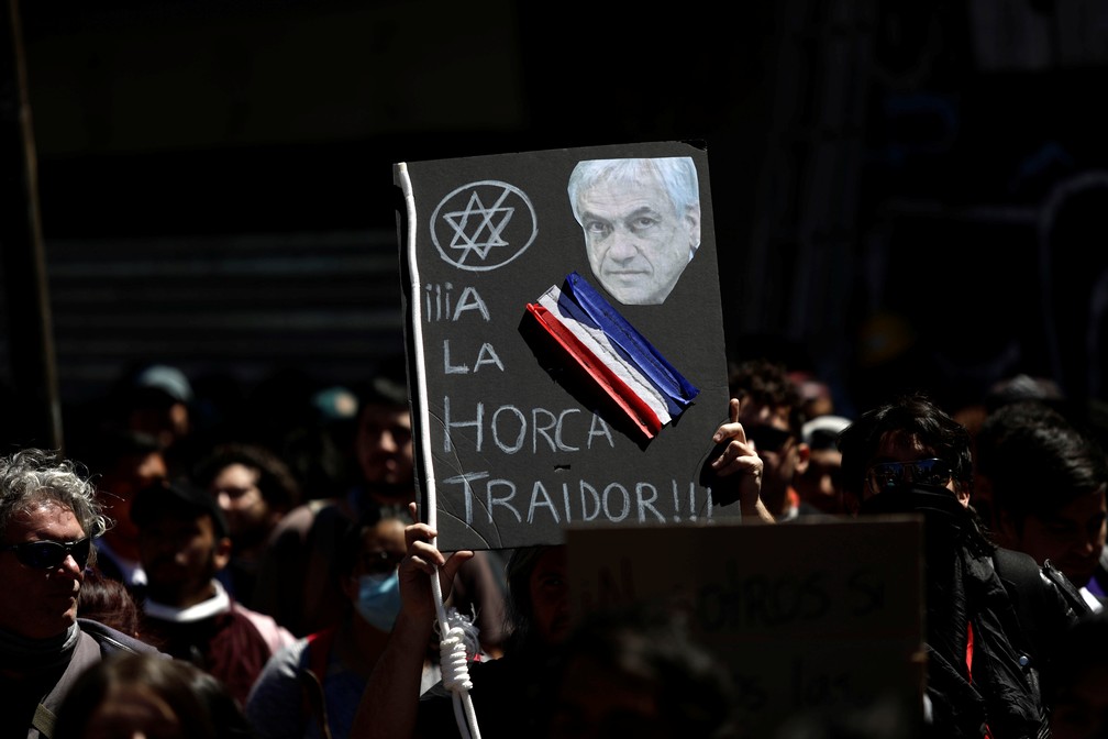 Manifestantes exibem cartaz com rosto do presidente do Chile, Sebastian Piñera: 'À forca, traidor' — Foto: Juan Gonzalez/Reuters