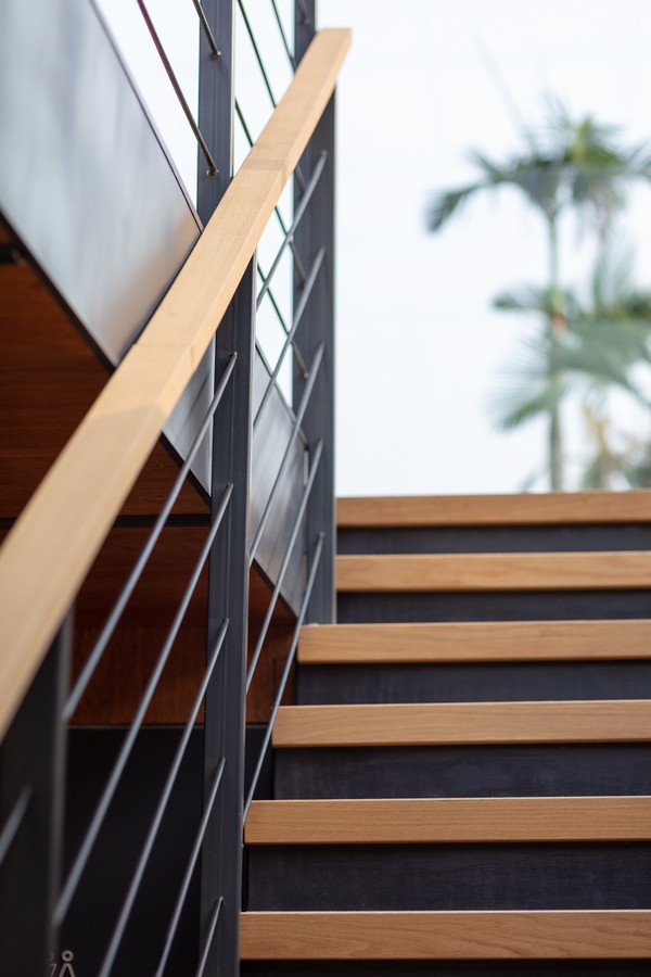Detalhe da escada de metal com corrimão de madeira que une os dois pavimentos 