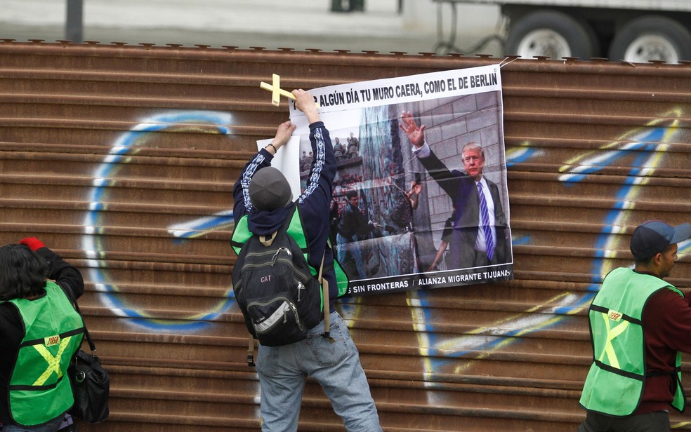 Manifestante pendura cartaz na fronteira do MÃ©xico com os EUA com os dizeres 'um dia seu muro cairÃ¡, como o de Berlim' (Foto: Reuters/Jorge Duenes)
