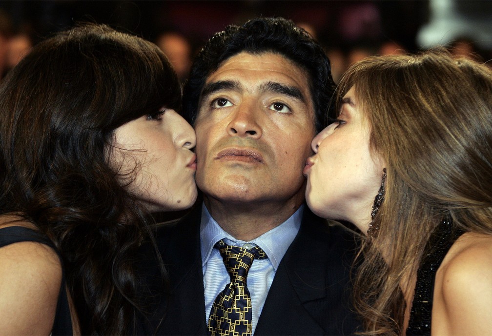 Diego Maradona é beijado pelas filhas Giannina Dinorah (esq.) e Dalma Nerea, posando para fotos antes da pré-estreia do filme 'Maradona' no Festival de Cinema de Cannes, na França, em maio de 2008 — Foto: François Mori/AP/Arquivo