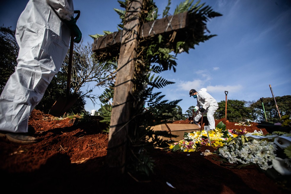 Funcionários vestindo roupas de proteção contra o coronavírus sepultam os corpos de vítimas da Covid-19 no Cemitério da Vila Formosa, na Zona Leste de São Paulo, na segunda-feira (29). — Foto: Werther Santana/Estadão Conteúdo 