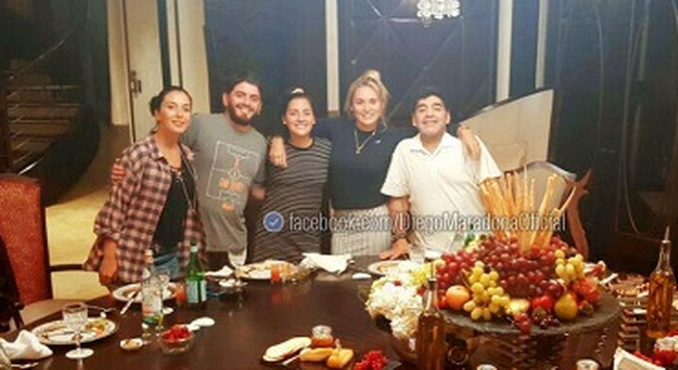 Maradona com filhos, nora e esposa em frente a mesa em sua casa em Dubai — Foto: Reprodução do Facebook