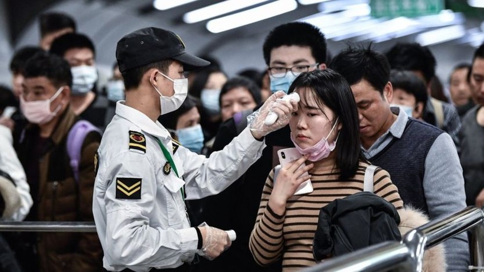 Viajantes passam por teste de temperatura corporal em aeroporto para detectar sintoma de febre causada por Coronavírus. — Foto: Getty Images