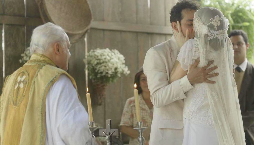 Zeca (Eduardo Sterblitch) e Olga (Maria Eduarda de Carvalho) se casam sob as bênçãos de Padre Venâncio (Othon Bastos) — Foto: Globo
