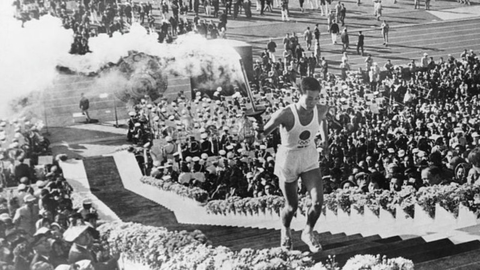 Milhares de espectadores presentes no Estádio Nacional de Tóquio se emocionaram ao ver o atleta Yoshinori Sakai (1945-2014) carregar a tocha na cerimônia de abertura dos Jogos — Foto: Getty Images via BBC