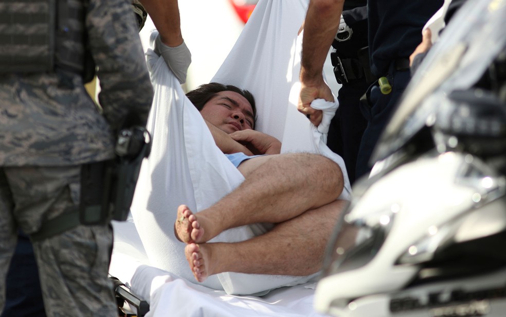 Um homem é levado por policiais da base Pearl Harbor — Foto: Caleb Jones / AP Photo