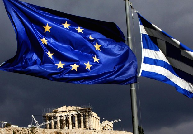 Bandeiras da Grécia e da União Europeia tremulam ao vento, tendo a Acrópolis de Atenas ao fundo (Foto: Getty Images)
