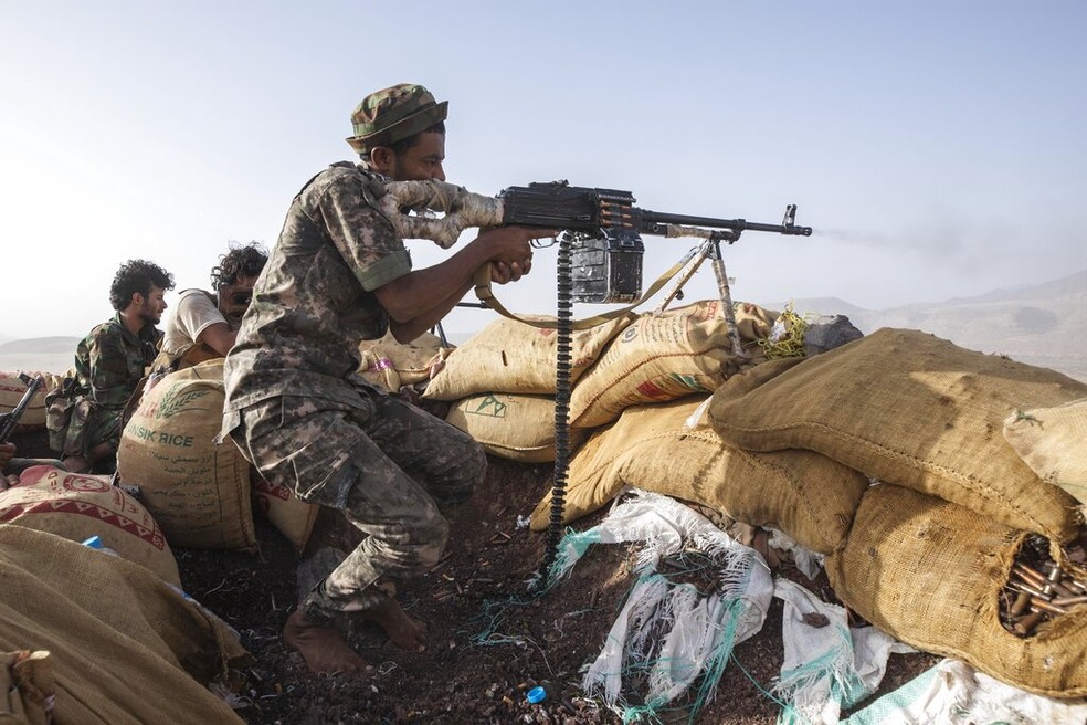 Um combatente iemenita apoiado pela coalizão liderada pela Arábia Saudita dispara sua arma durante confrontos com rebeldes Houthi na linha de frente de Kassara perto de Marib, Iêmen, 20 de junho de 2023 — Foto: AP Photo/Nariman El-Mofty