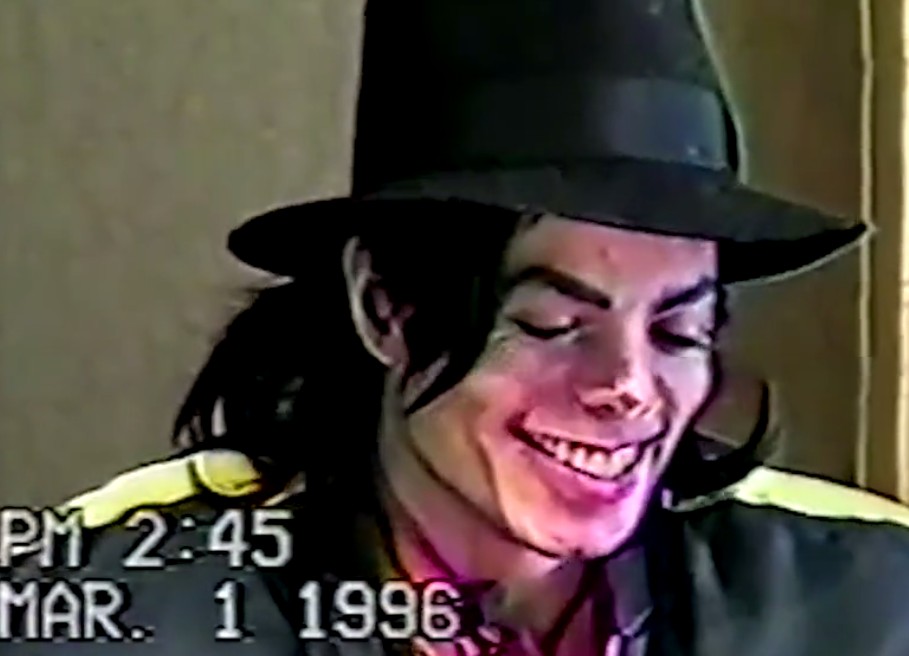 O cantor Michael Jackson (1958-2009) sorrindo em meio ao depoimento dele no ano de 1996 sobre as acusações de abusos de menores (Foto: Reprodução)