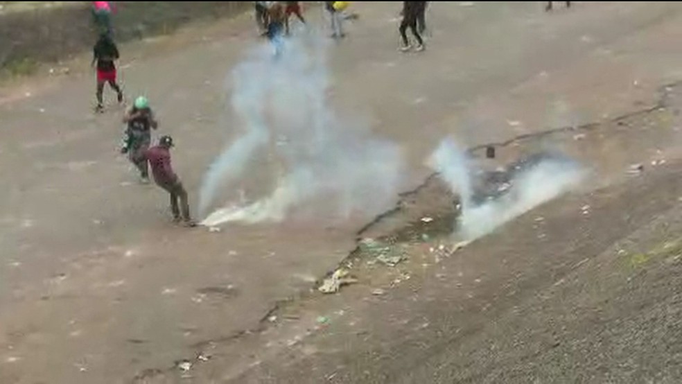 Manifestante chuta bomba de gás jogada pela Guarda Bolivariana em conflito em Pacaraima em 23/02/19 — Foto: Reprodução/GloboNews