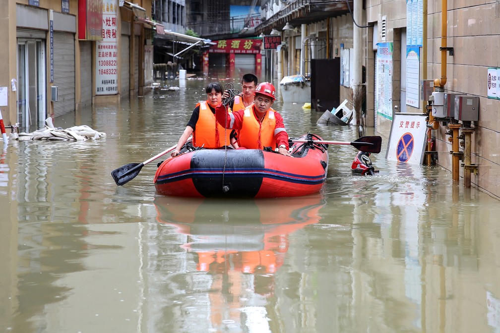 Equipes de resgate evacuam os moradores afetados por enchentes após uma forte chuva em Neijiang, na província de Sichuan, no sudoeste da China, nesta terça-feira (18) — Foto: AFP