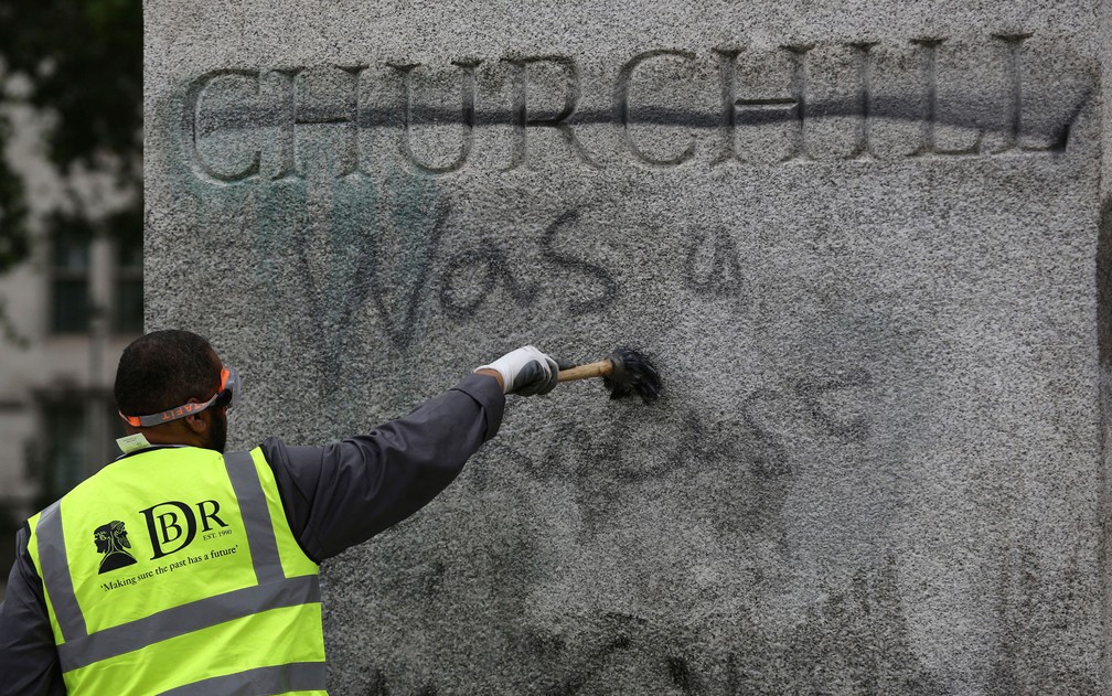 Funcionário limpa pichação da estátua de Sir Winston Churchill na Parliament Square, em Londres, na segunda-feira (8) — Foto: Aaron Chown/PA via AP