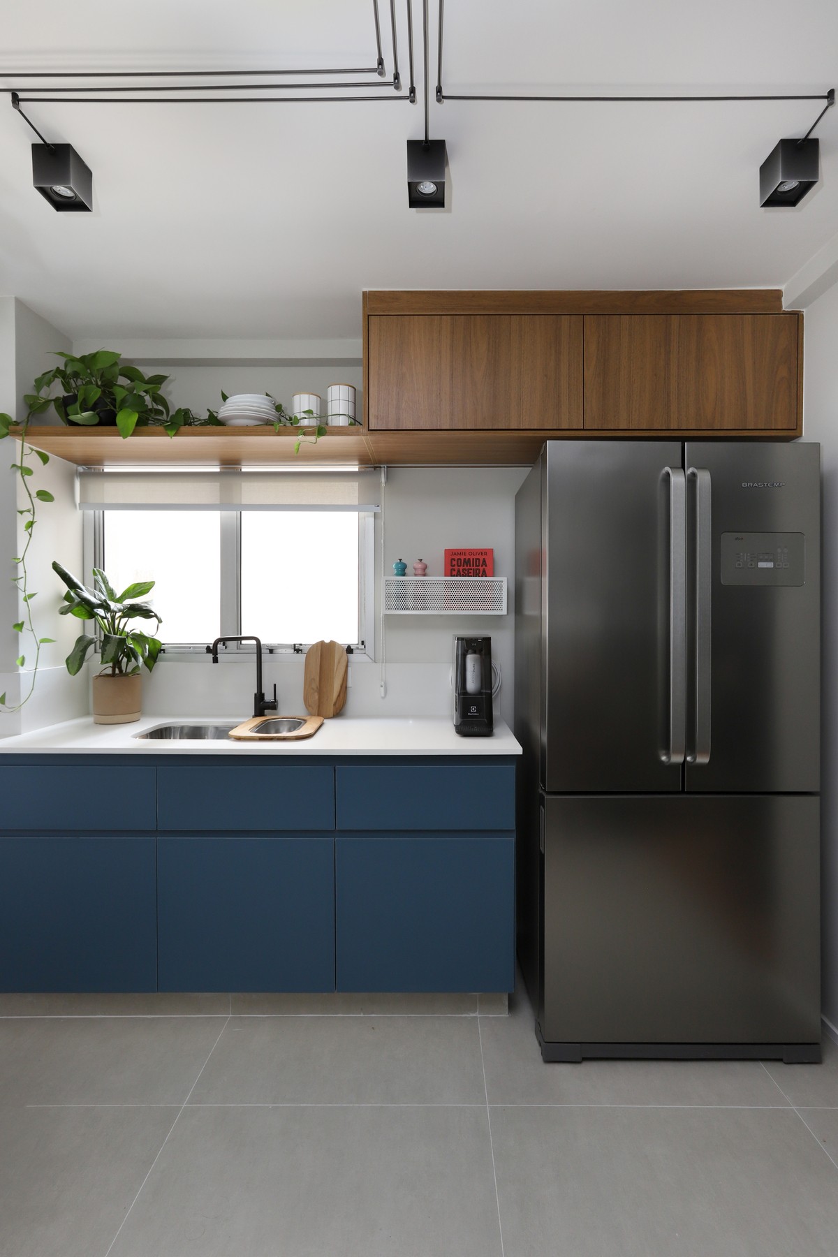 COZINHA | Na cozinha, o tampo da bancada é em quartzo branco e os armários e gavetões em fórmica azul escura trazem contraste (Foto: Mariana Orsi /  Divulgação)