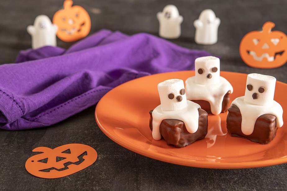 Os fantasminhas são feitos de marshmallow com pequenas gotas de chocolate sobre pão de mel