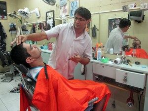 Gilvan trabalha mais de 12 horas, seis vezes por semana, na barbearia na entrada da Rocinha (Foto: Tássia Thum/G1)