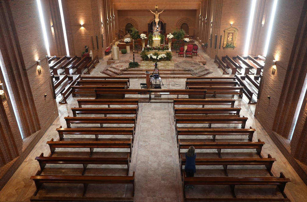 12 de abril - Uma mulher se ajoelha ao rezar após a missa do domingo de Páscoa em uma paróquia vazia de Santa Maria de Cana em Pozuelo de Alarcon, na Espanha, em meio ao surto do coronavírus — Foto: Sergio Perez/Reuters