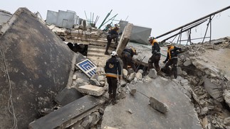 Membros da defesa civil síria, conhecidos como Capacetes Brancos, procuram vítimas sob os escombros após um terremoto na cidade de Sarmada, no interior da província de Idlib, em 6 de fevereiro de 2023 — Foto: Mohammed Al-Rifai / AFP