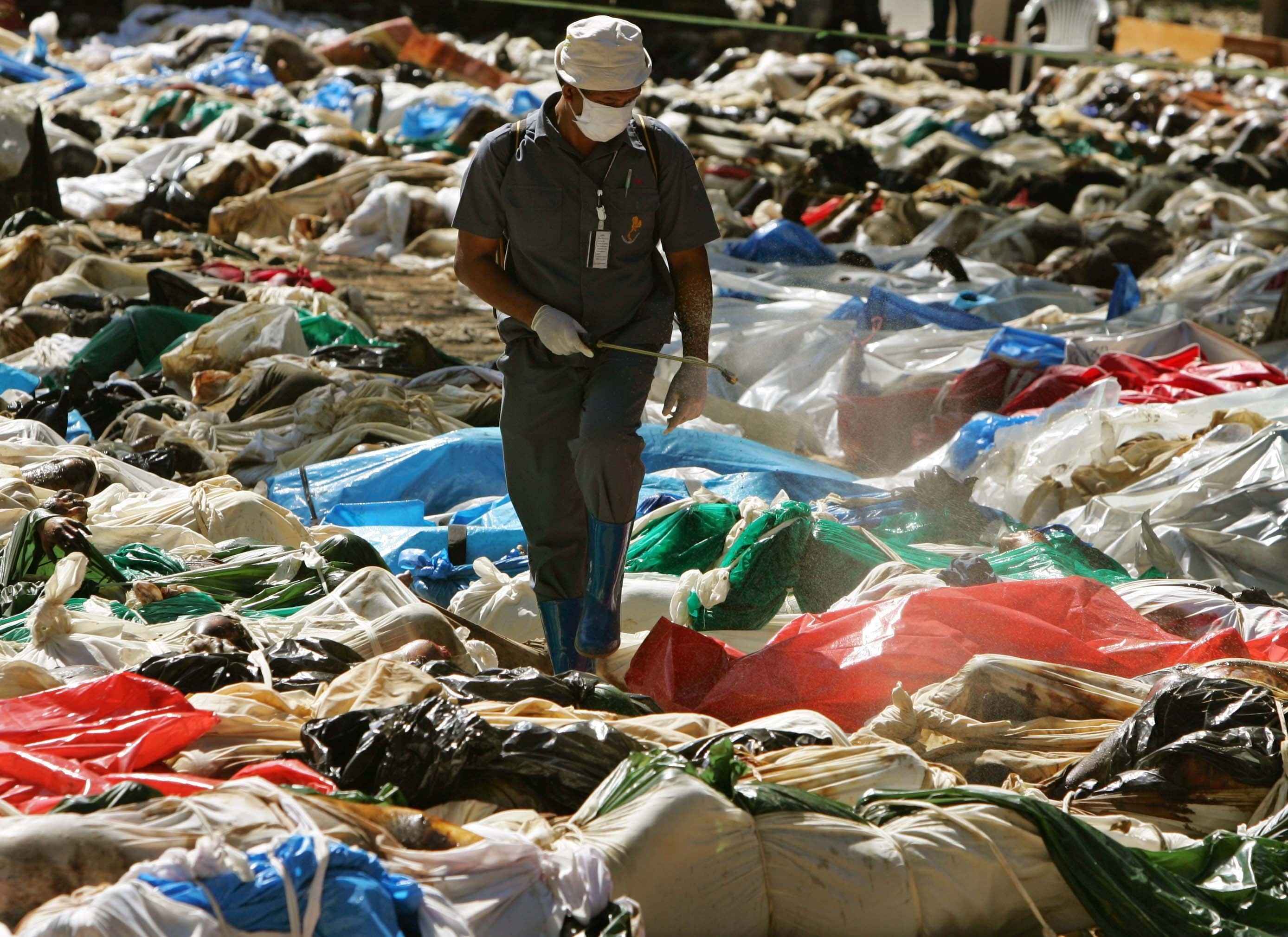 Agente de saúde tailandês caminha entre corpos de pessoas mortas na Tsunami, em 2004