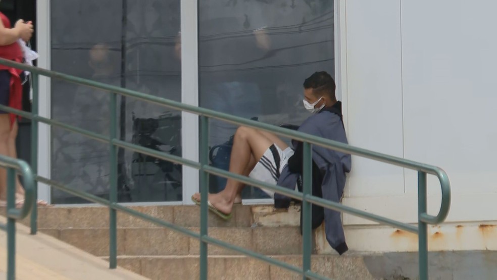 Paciente aguarda atendimento sentado do lado de fora de UPA, no DF — Foto: TV Globo/Reprodução