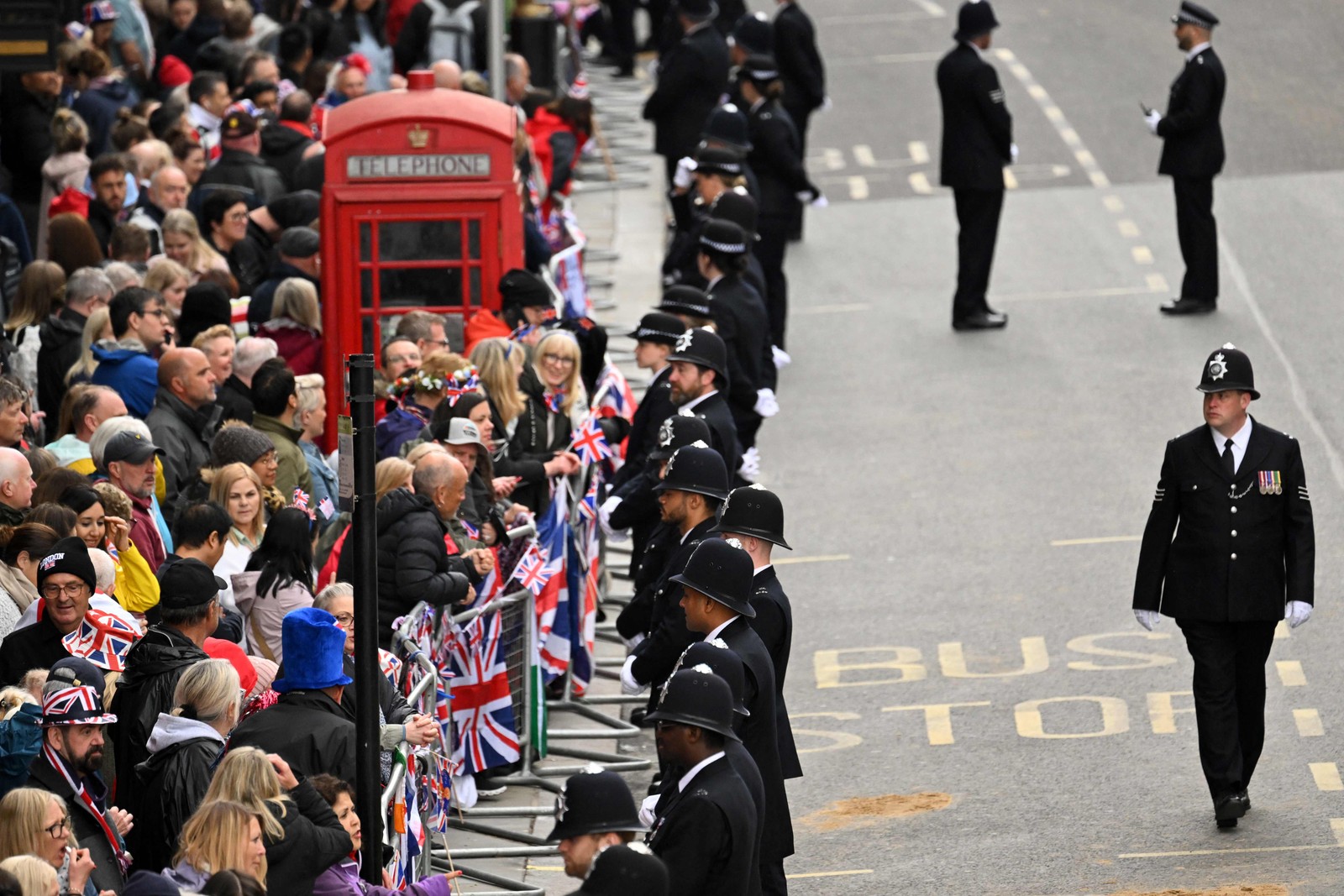 Policiais fazem a segurança diante do público em avenida por onde passará a "Procissão do Rei", no centro de Londres — Foto: SEBASTIEN BOZON/POOL/AFP