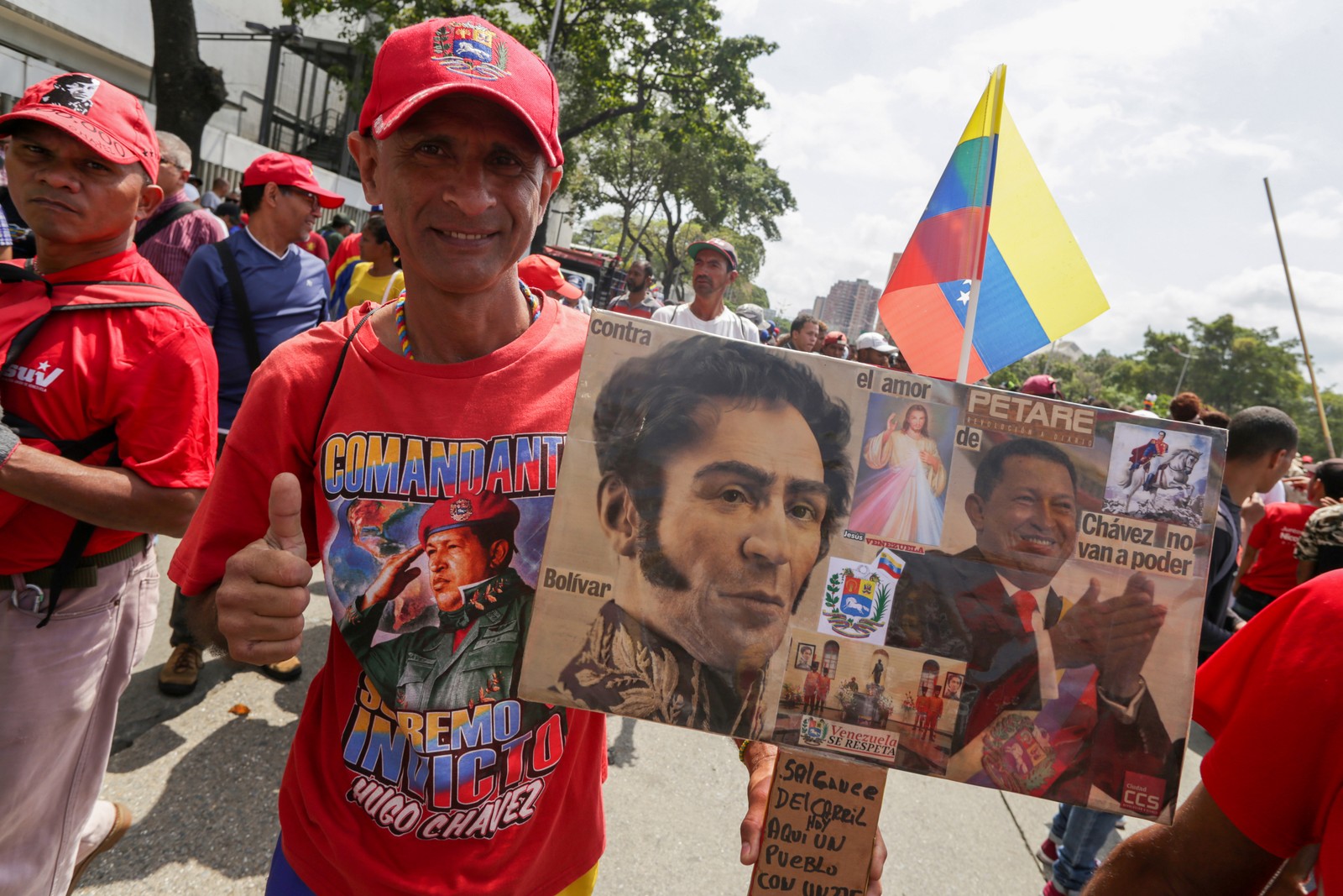 Manifestante pró-Maduro leva cartaz com imagens de Hugo Chavez e Simon Bolívar. — Foto: Cristian Hernandez / AFP