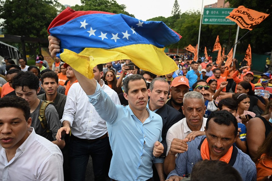 O líder da oposição venezuelana Juan Guaidó agita uma bandeira nacional durante uma manifestação para exigir uma data para as eleições presidenciais, em Caracas