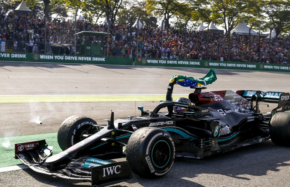 Com a bandeira brasileira em punho, Lewis Hamilton passa pelas arquibancadas da reta dos boxes no GP de São Paulo de 2021 — Foto: Jiri Krenek
