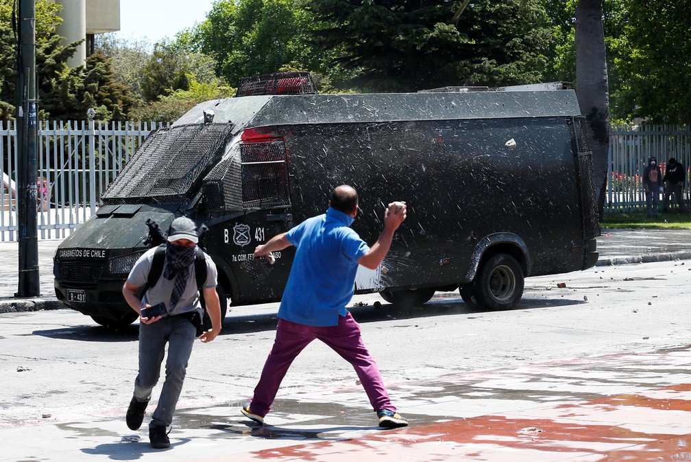 Manifestante atira pedra em veículo de forças de segurança em Valparaíso, no Chile, em protesto nesta sexta-feira (25) — Foto: Rodrigo Garrido/Reuters