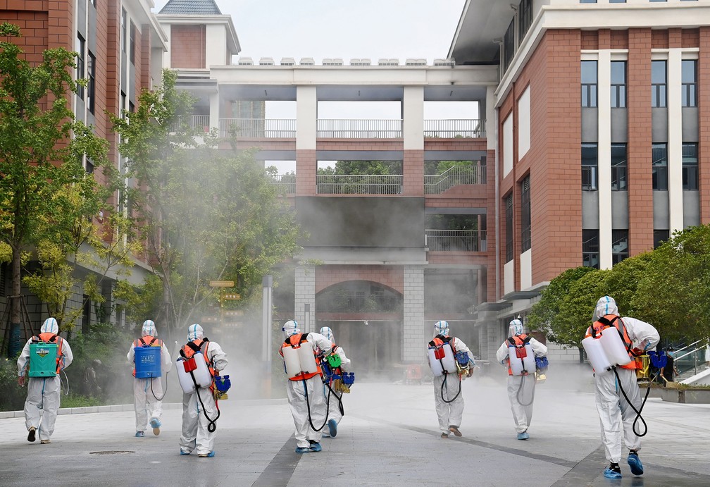 Grupo usando trajes de proteção desinfeta escola primária em 25 de agosto de 2021 em Wuhan, na China, antes de sua reabertura no próximo semestre, após surto de Covid-19 na província de Hubei — Foto: China Daily via Reuters